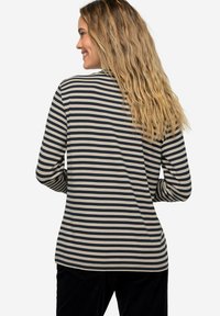 Halenka s dlouhým rukávem v béžové a námořnické modré barvě s vodorovnými pruhy, vyrobená z měkké tkaniny, s uvolněným střihem a kulatým lemováním.