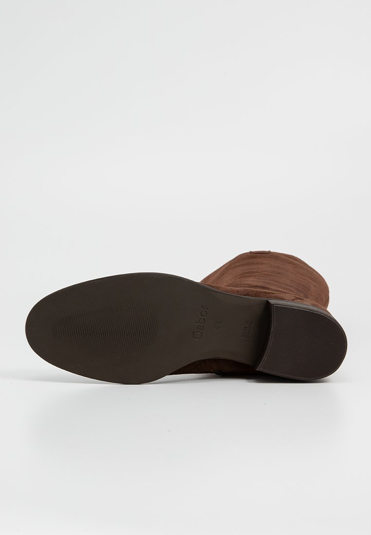 Brązowy zamszowy botek za kostkę z gładkim, zaokrąglonym czubkiem i niskim gumowym obcasem. Dół pokazuje teksturowaną podeszwę z brandingiem Gabor.