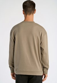 Felpa beige a girocollo con polsini e orlo a coste, realizzata in morbido tessuto con una superficie liscia, caratterizzata da una vestibilità comoda e design minimal.