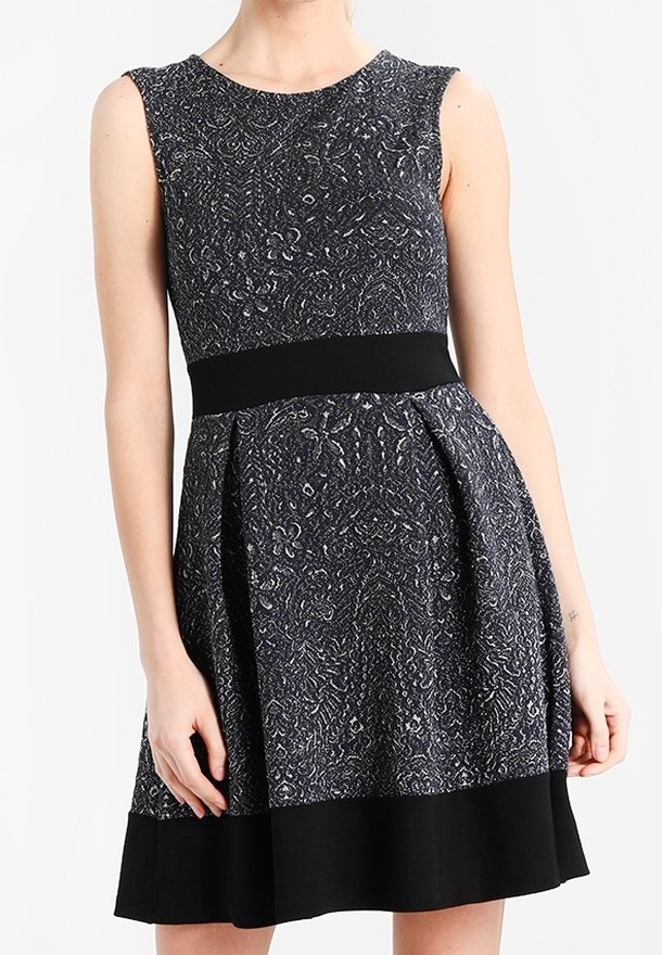 Schwarz-weiß gemustertes ärmelloses Kleid mit tailliertem Oberteil, schwingendem Rock und einfarbigem schwarzen Bund. Texturiert, knielang.