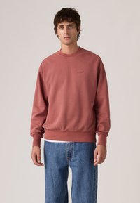 Φούτερ με στρογγυλή λαιμόκοψη σε αποχρώσεις dusty rose, με ριμπ μανσέτες και στρίφωμα. Διαθέτει διακριτικό λογότυπο στο στήθος και άνετη εφαρμογή, συνδυασμένο με μπλε τζιν.