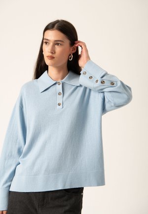 Lichtblauwe gebreide pullover met een kraag, een sluiting met drie knopen en met knopen afgewerkte mouwen. Zacht textuur en een relaxte pasvorm.