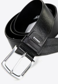 Zwarte leren riem met een gladde textuur, afgewerkt met een zilveren metalen gesp en een leren accent met merklogo. De riem is stijlvol en stevig.