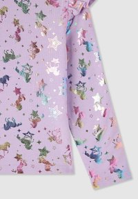 Lawendowa bluzka z długim rękawem, ozdobiona błyszczący, wielokolorowym wzorem jednorożców i gwiazd, o miękkiej strukturze i lekkim falbance.