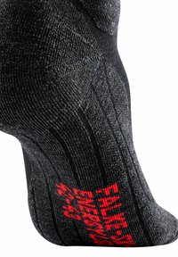 Calcetín negro con tejido texturizado y diseño acanalado. Texto rojo notable en el costado que dice "Energía" junto con información de la talla.