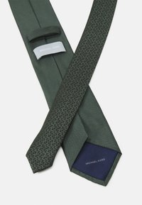 Grønn slips med teksturert mønster, som har en ensfarget front og en blå fôr. Inkluderer Michael Kors-merke på etikettene.