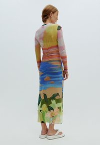 Robe longue et ajustée avec un imprimé paysage coloré aux tons rose, bleu et vert. Confectionnée dans un tissu léger et texturé, avec des manches longues.