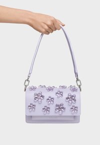 Lilac leather handbag with floral embellishments and transparent accents. Features a top handle and silver hardware. Compact rectangular shape.