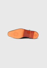 Svart skosåle med oransje skinnaksenter. Har en glatt finish, preget logo og flat design for stabilitet.