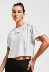 T-shirt de sport blanc à manches courtes, avec une texture de tissu lisse et un petit logo noir "Redmax" sur la poitrine.