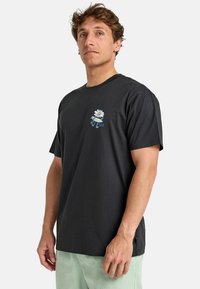 T-shirt en coton noir à manches courtes, avec un motif de marguerite et un logo sur la poitrine gauche. Texture douce et design décontracté.