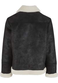 Zwarte suède jas met witte nepbontkraag, manchetten en zoom, gezien van achteren.