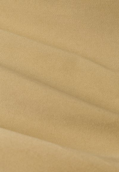 Tessuto beige con una superficie morbida e texturizzata, caratterizzato da pieghe diagonali e un sottile motivo a coste, che crea profondità e interesse visivo.