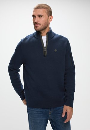 Pullover a maglia blu navy con colletto a mezza zip, caratterizzato da un tessuto testurizzato, un patch rotondo con logo e una tasca con zip sulla manica sinistra.