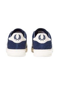 Zapatillas de ante en color navy con detalles en cuero blanco. Presenta un logo con diseño de corona de laurel en el talón. Suela de goma. Estilo casual.