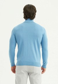 Pull bleu clair avec des manches longues, un col montant, et des poignets et un bas côtelés. Fabriqué dans un tissu doux et lisse.