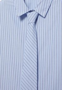 Chemise habillée bleu clair avec fines rayures verticales bleu marine, associée à une cravate bleu clair assortie présentant des rayures diagonales.