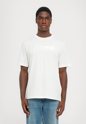Camiseta de algodón blanca con cuello redondo y mangas cortas, con "justcavalli" impreso en un tono plateado sutil en el pecho.