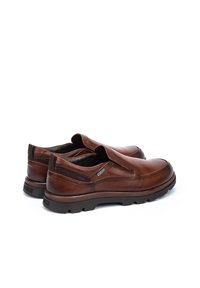 Zapatos de cuero marrón tipo mocasín con punta redondeada, detalles de costura sutil, cuello acolchado y suela de goma texturizada.