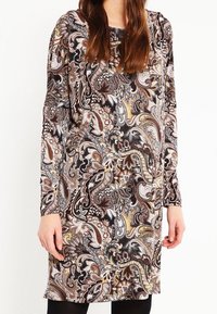 Długa tunika z długim rękawem w wzór paisley w odcieniach brązu, złota i czerni. Wykonana z miękkiego materiału o luźnym kroju i okrągłym dekolcie.