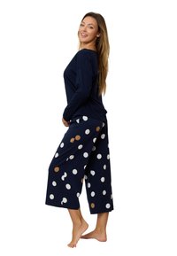 Granatowa bluzka z długim rękawem w połączeniu z wzorzystymi granatowymi kulotami w białe i brązowe kropki. Miękka tkanina o luźnym kroju.