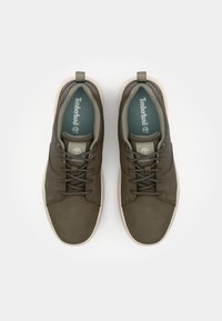 Dark green leather sneakers with a smooth texture, round toe, and rounded laces. Light tan rubber soles and Timberland logo on the tongue.