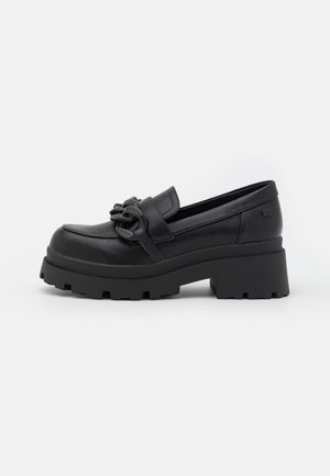 Mocassins en cuir noir à talon plateforme avec une semelle épaisse et texturée. Dotés d'une sangle tressée sur le devant et d'un design à bout rond.