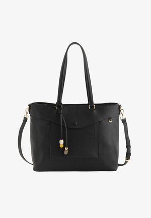 Bolso tote negro con dos asas, correa de hombro desmontable, bolsillito frontal con solapa y botón, y cuentas decorativas en un cordón de cuero.