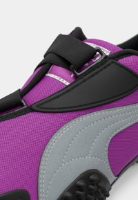 Lilla mesh sneakers har et grått aksentdesign, svarte stropper og en teksturert gummisåle med runde fremspring for grep.