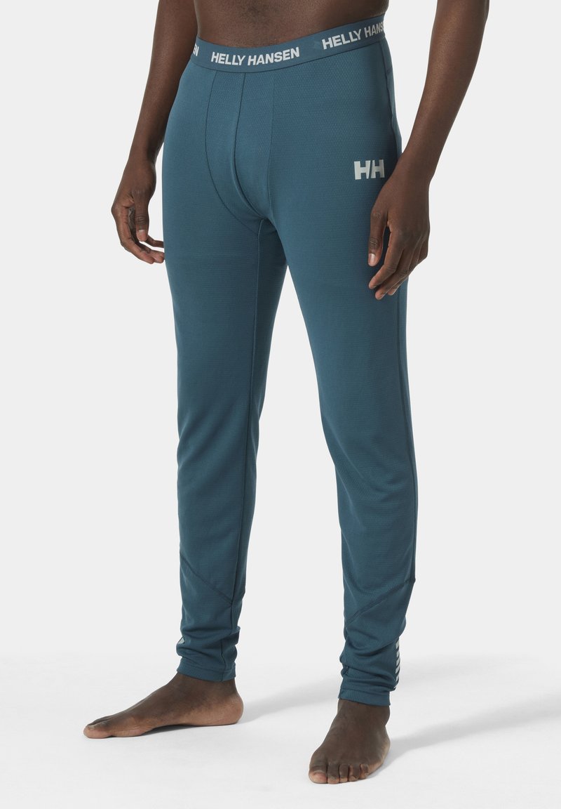 Pánské termo legíny v tónech modrozelené s elastickým střihem. Vlastnosti zahrnují texturovanou látku a logo Helly Hansen na pásku a po straně.