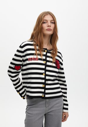 Cardigan a righe bianche e nere con ricami rossi e bottoni dorati. Presenta motivi a cuore e floreali. Tessuto morbido a maglia.