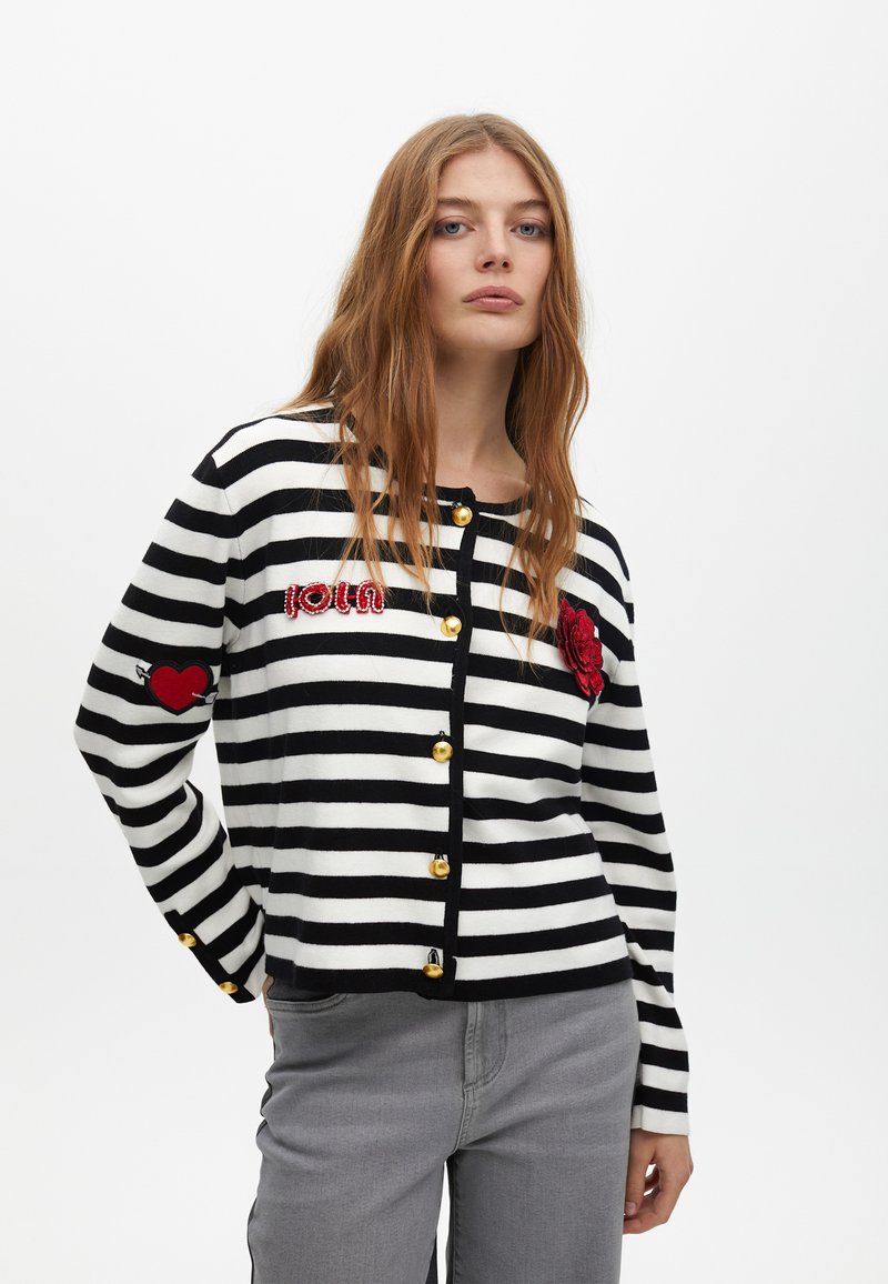 Sweter w paski czarno-biały z czerwonymi haftami i złotymi guzikami. Posiada wzory serc i kwiatów. Miękka dzianina.