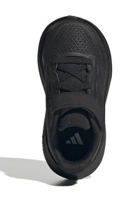 Svart idrottssko med en strukturerad mesh-överdel, snörning och ett band för en säker passform. Distinkt logotyp synlig på innersulan.