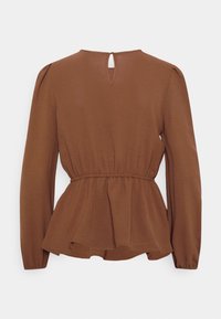 Brązowa bluzka z długim rękawem i krojem peplum, z detalem w kształcie otworu na plecach oraz miękkim, teksturowanym materiałem. Gładkie szwy w całej bluzce.