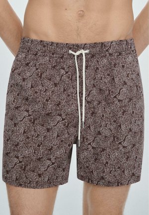Pantaloncini da uomo marroni con un elaborato motivo paisley chiaro e cordino bianco, indossati da una persona senza maglietta.