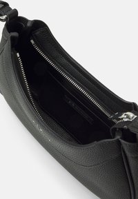 Czarna torba na ramię z teksturowanej skóry z srebrnym zamkiem i wewnętrzną kieszenią oznaczoną marką Armani Exchange.