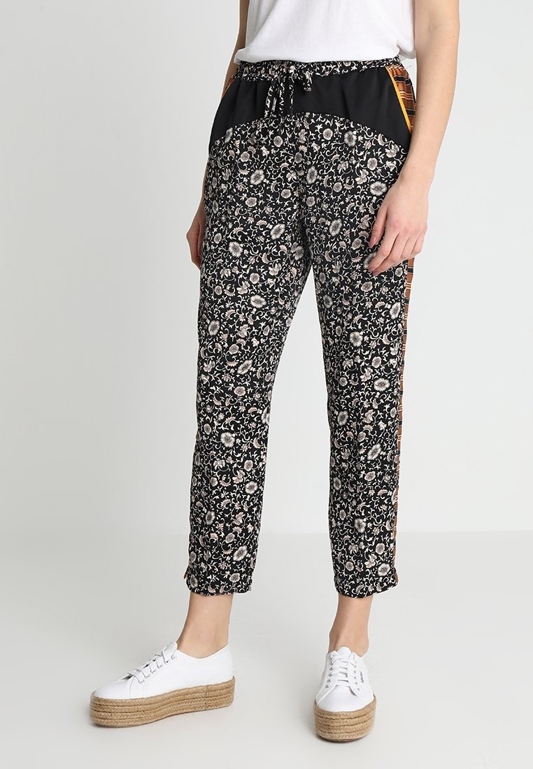 Zwarte bloemenprint broek met een zwarte tailleband, trekkoord en zijaccenten. Gecombineerd met witte platform sneakers.