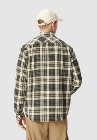 Herren-Flanellhemd mit großem Karomuster in Creme, Grün und Braun, ausgestattet mit einem Button-Down-Kragen und langen Ärmeln.