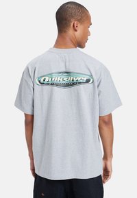 Grey short-sleeve t-shirt featuring a large, multicolored Quiksilver logo in the center of the back. Soft cotton material.