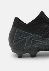 Scarpe da calcio nere con superficie testurizzata, colletto alto e un motivo geometrico distintivo in una tonalità più scura, con tacchetti sagomati.