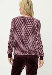 Langärmeliges Oberteil in Burgunderrot mit einem geometrischen pinkfarbenen Muster, ausgestattet mit einem Rundhalsausschnitt und engen Bündchen. Glatte Stoffstruktur.