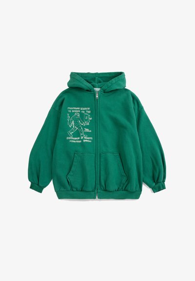 Veste à capuche zippée verte avec poches avant et illustration blanche d'un Yéti en marche ainsi que du texte sur le côté gauche de la poitrine.