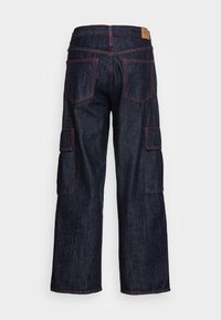 Mörkblå vida jeans med bakfickor, cargo fickor på varje ben, och kontrasterande röda sömmar.
