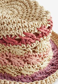 Bols en osier tressés empilés, fabriqués à partir de fibres naturelles texturées dans des teintes beige, rose et violet, présentant un motif alterné et un tissage ouvert.