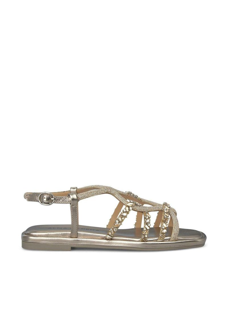 Sandalias planas metálicas doradas con tiras cruzadas decoradas con cuentas, hebilla ajustable y suela plana para mayor comodidad.