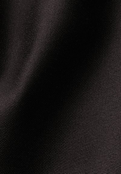 Gros plan d'un tissu noir tissé montrant une texture détaillée et un petit motif tricoté serré avec des plis doux.