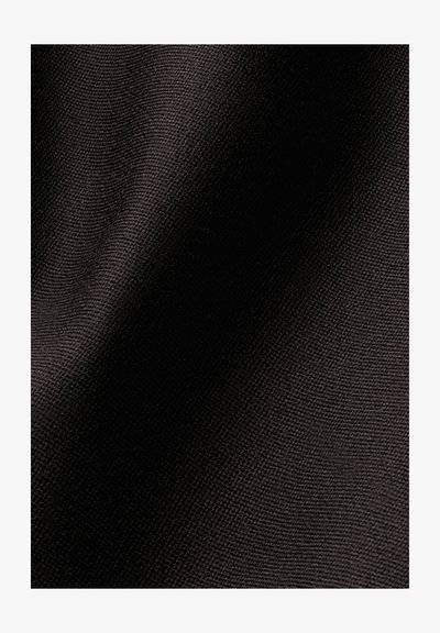 Gros plan d'un tissu noir tissé montrant une texture détaillée et un petit motif tricoté serré avec des plis doux.