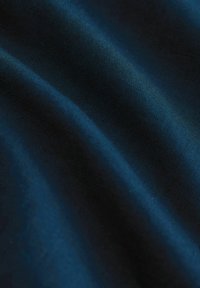 Gros plan d'un tissu bleu foncé avec des plis doux et une texture tissée visible.