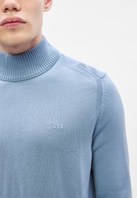 Ανοικτό μπλε ζιβάγκο φανέλα φτιαγμένο από λεπτό ύφασμα, με ριμπ κολάρο και το κεντημένο λογότυπο "BOSS" στο στήθος.