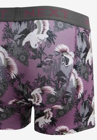 Men's boxer shorts in purple fabric featuring a pattern of cranes and floral designs. Elastic waistband with "NEXT" branding in gray.